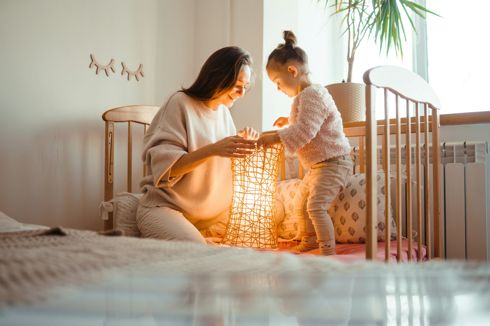 Cheerful mother and her little daughter watching at the lamp. Happy loving family.